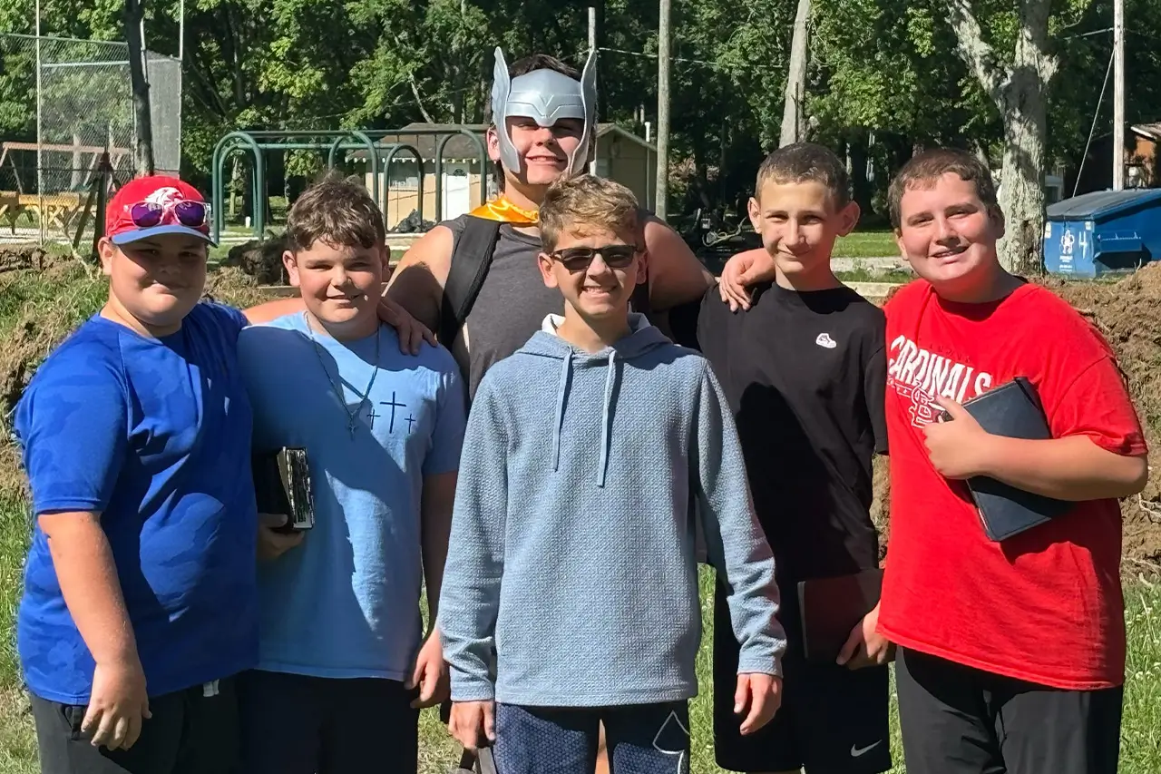 Six boys posing together outdoors near a playground structure