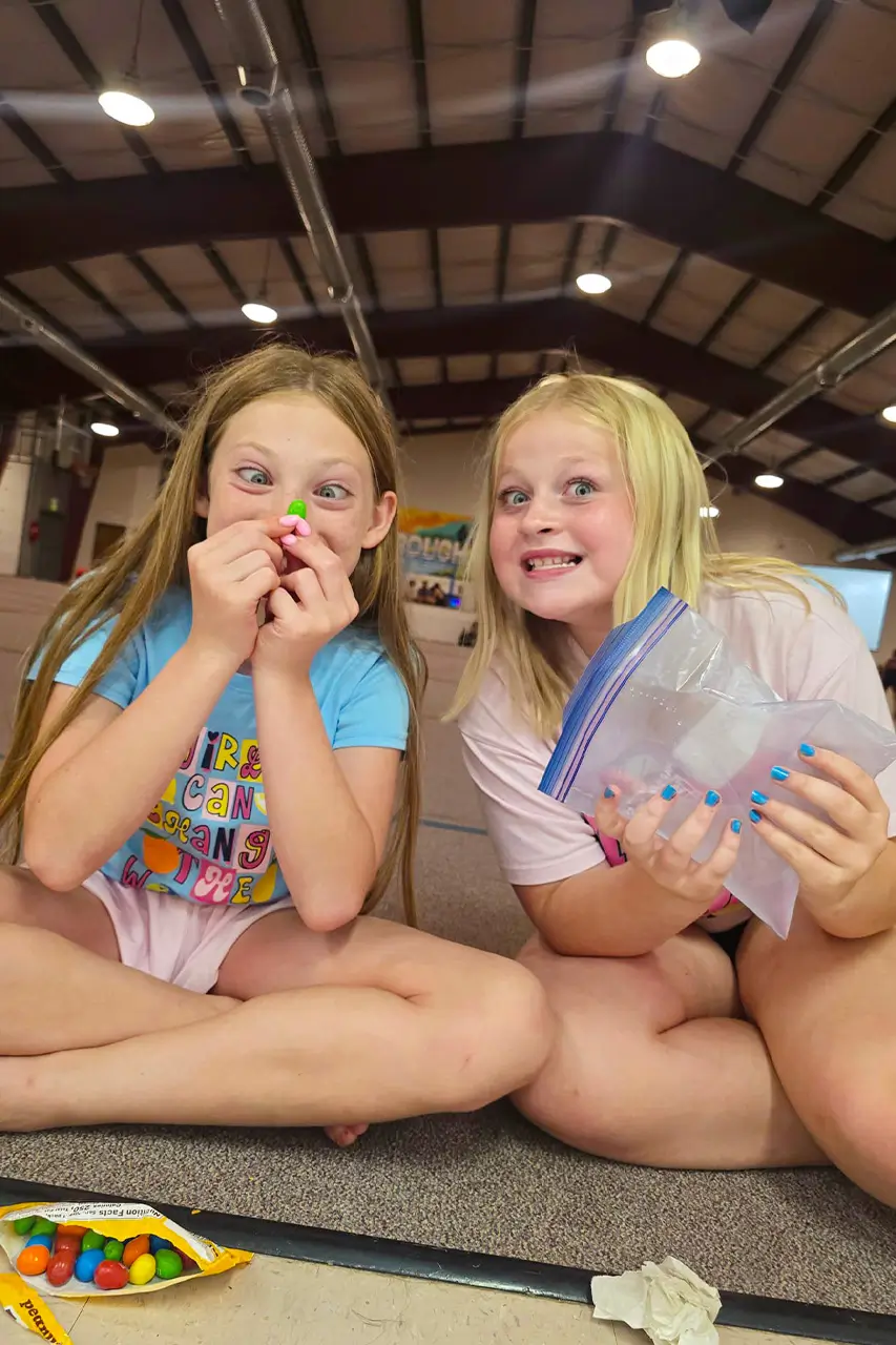 Two campers sharing candy during an indoor break