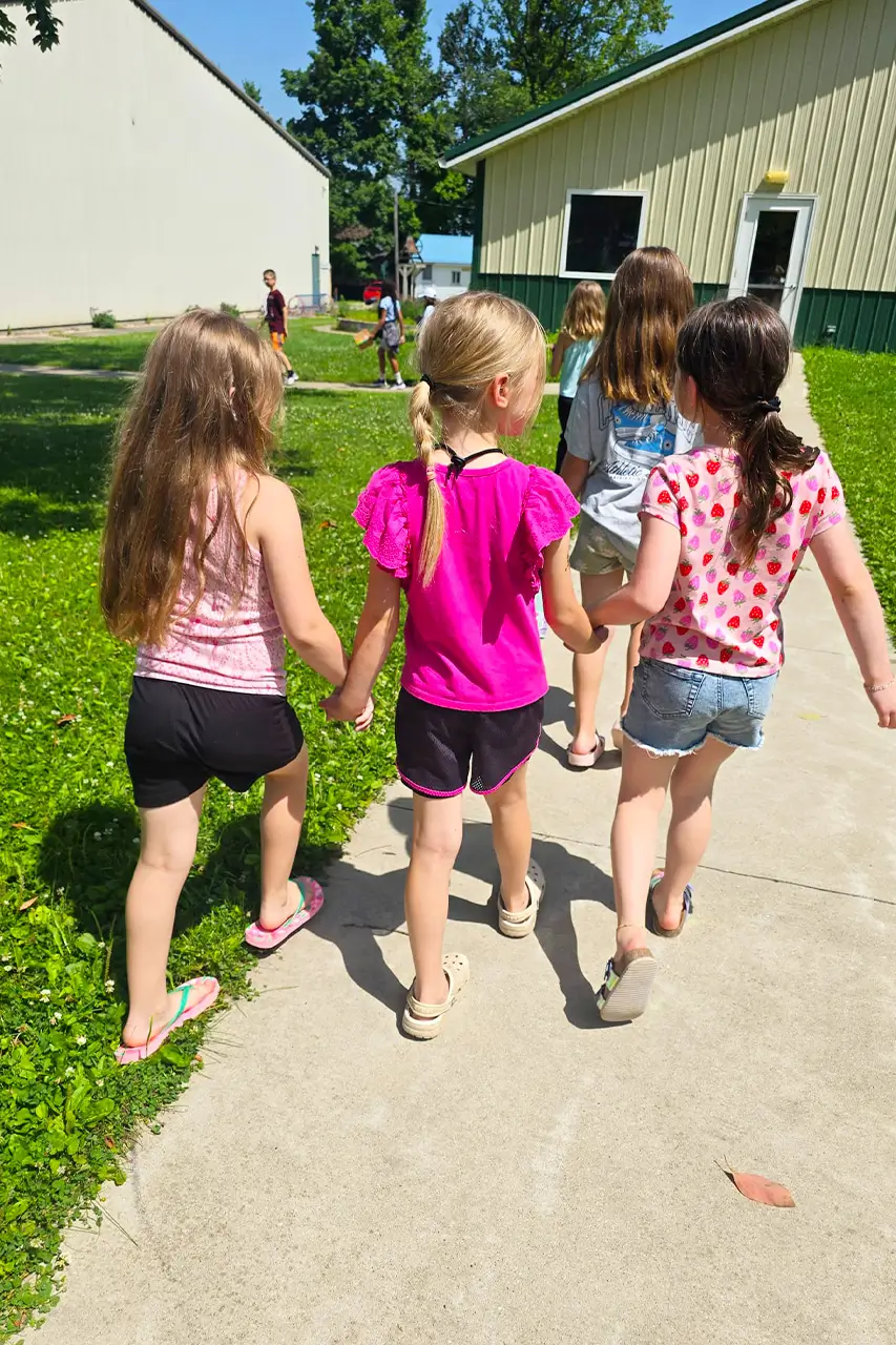 Group of campers walking together on a sidewalk near camp buildings