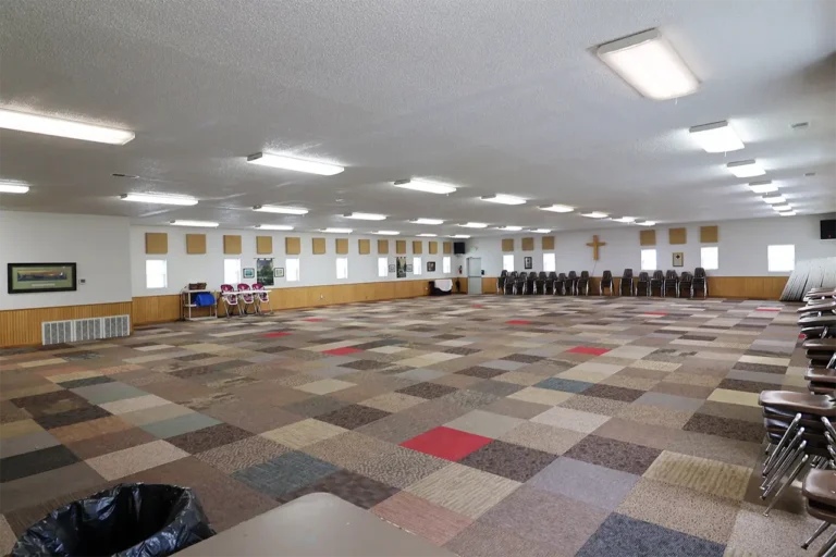 Multipurpose room with patterned carpet tile and stacked chairs