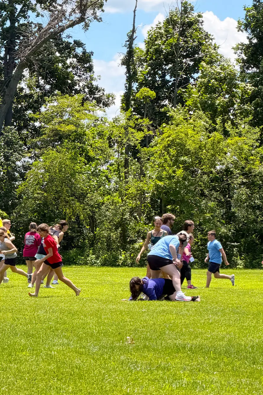 Campers piled together playing a game on the grass field