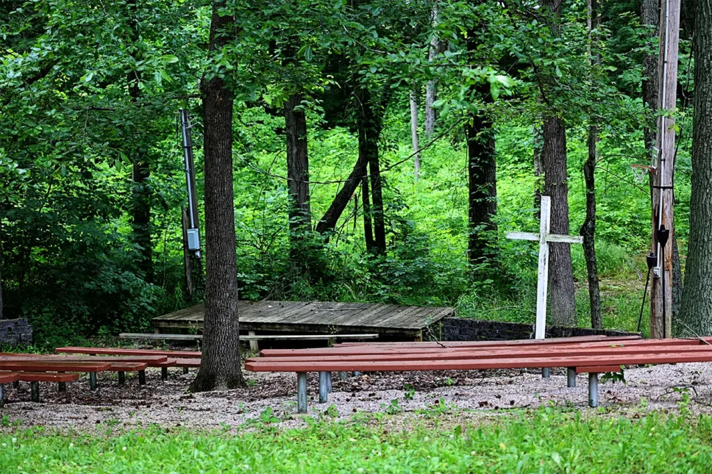 Outdoor church amphitheater with wooden cross and bench seating