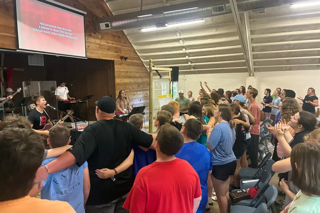 Campers and worship band singing together during an indoor worship service